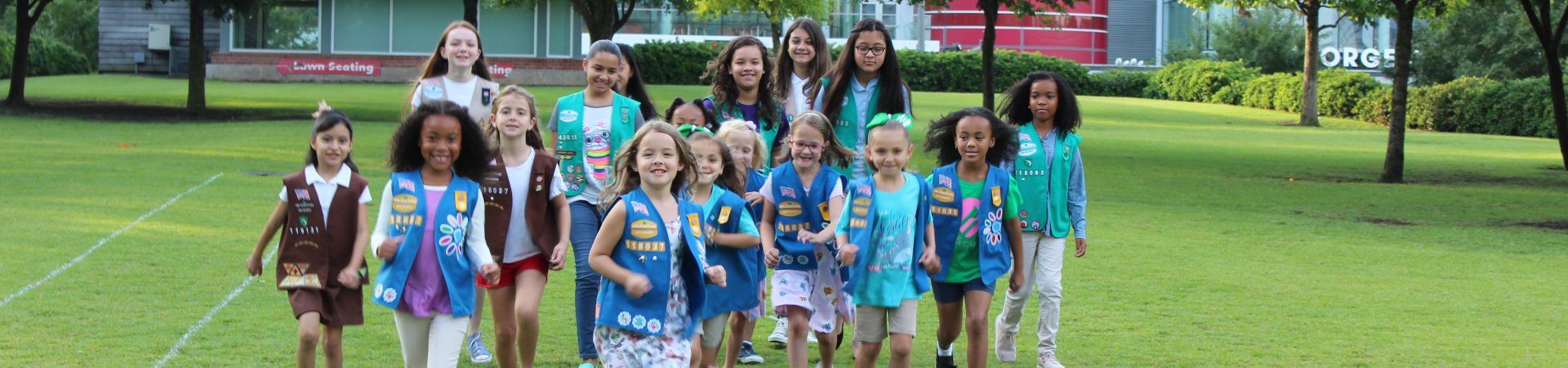  group of girl scouts walking outside smiling at camera 