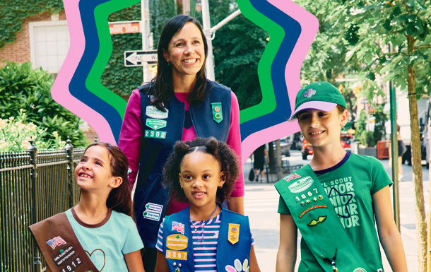 Volunteer walking on a sidewalk with three Girl Scouts.