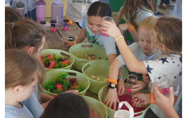 Group of Brownies gathered at table participatin in an art activity at camp.