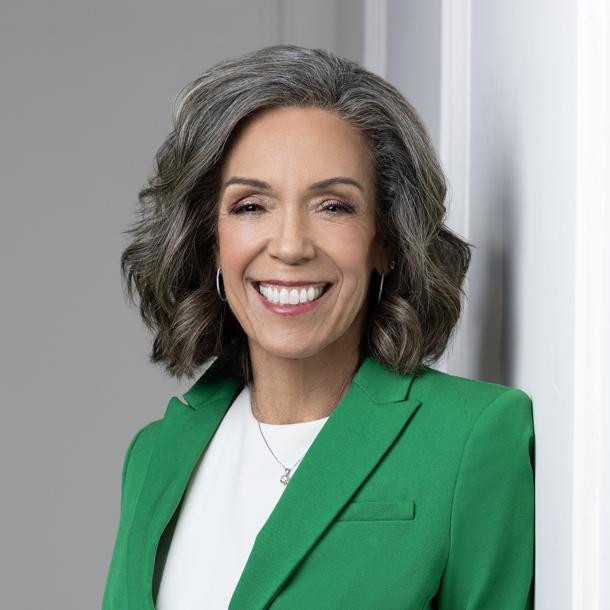 Headshot of women wearing white blouse and green blazer.