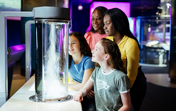 Volunteer with group of girls at a table with laptop.