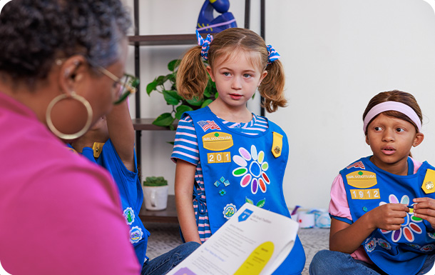 Troop leader with two girls in Daisy uniforms.