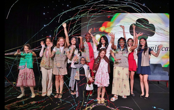 Group of excited Girl Scouts with raised hands surrounded by confetti