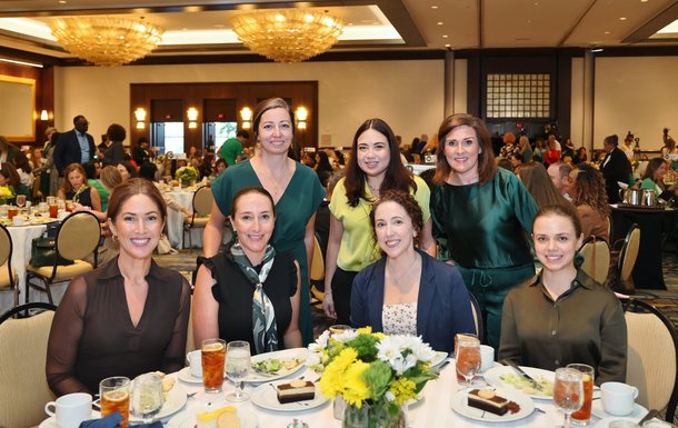 Seven women posed at lunchon table.